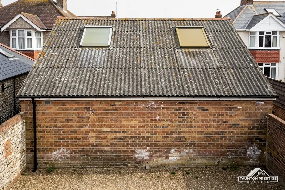 Old brick workshop with a corrugated cement sheet roof and two rooflights