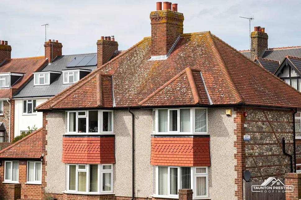 Pair of 1930s semis with hipped clay tile roofs, brick chimneys and two-storey bays