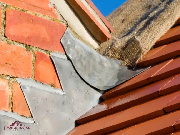 Close-up of lead step flashing dressed against red brick above clay tiles