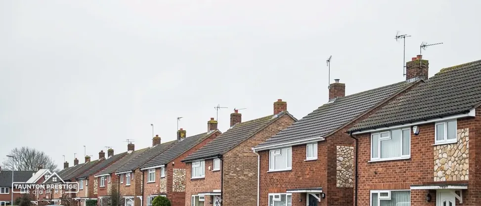 Street of brick semi-detached houses and their roofs seen from the pavement