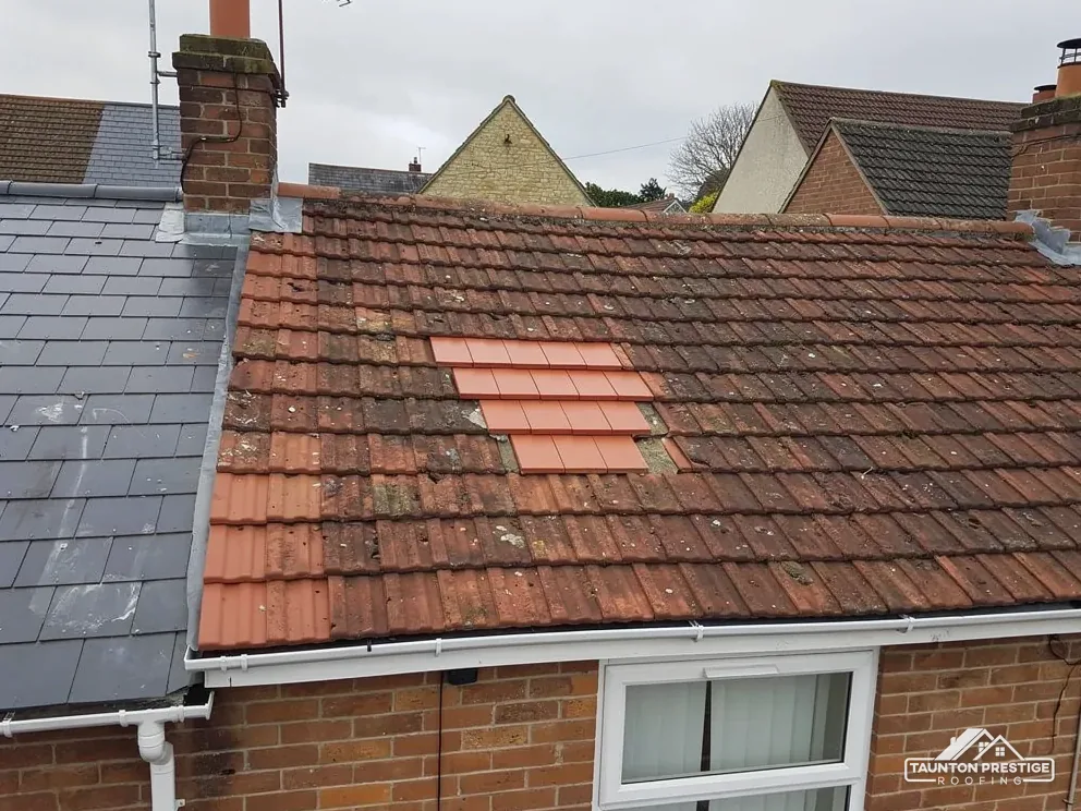 Patch of new clay tiles let into a weathered clay tile roof