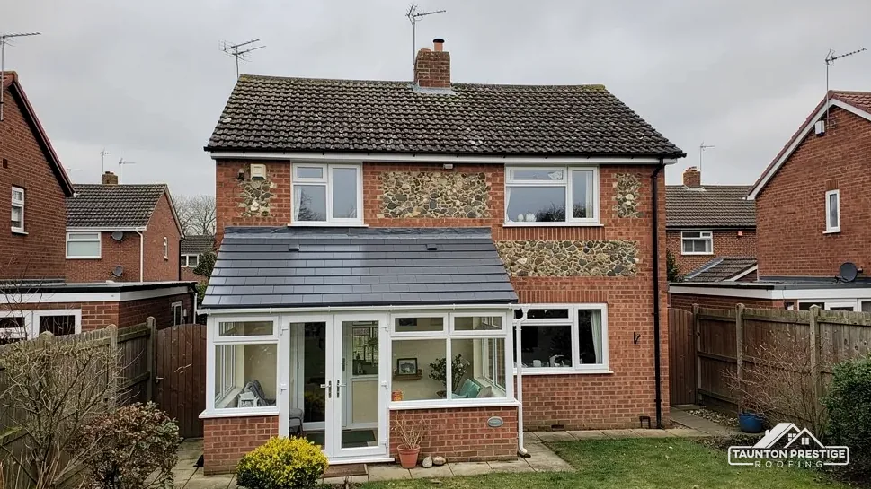Rear of a brick house with a conservatory under a solid tiled roof
