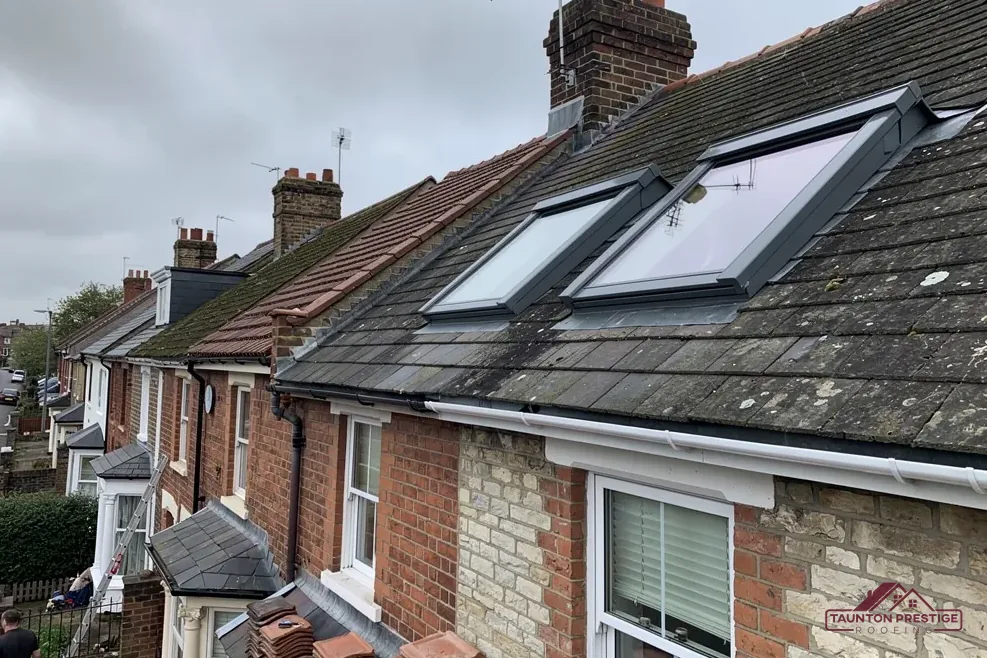 Two grey-framed roof windows in the slate roof of a terraced house