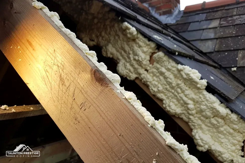 Spray foam stuck to a rafter and the underside of a tiled roof