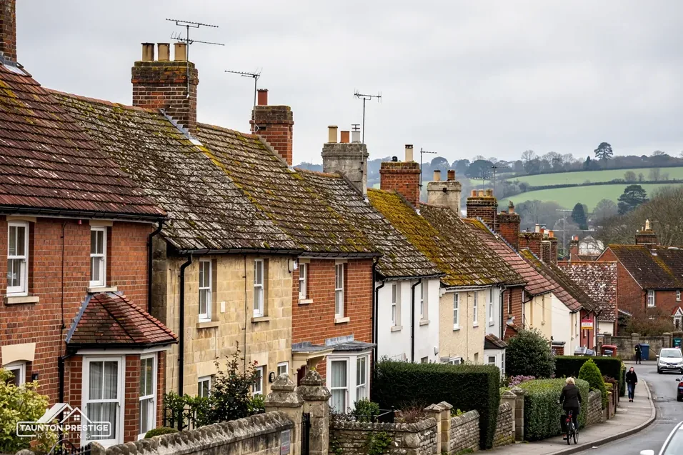 Street of red brick and stone cottages with clay tile roofs and chimneys