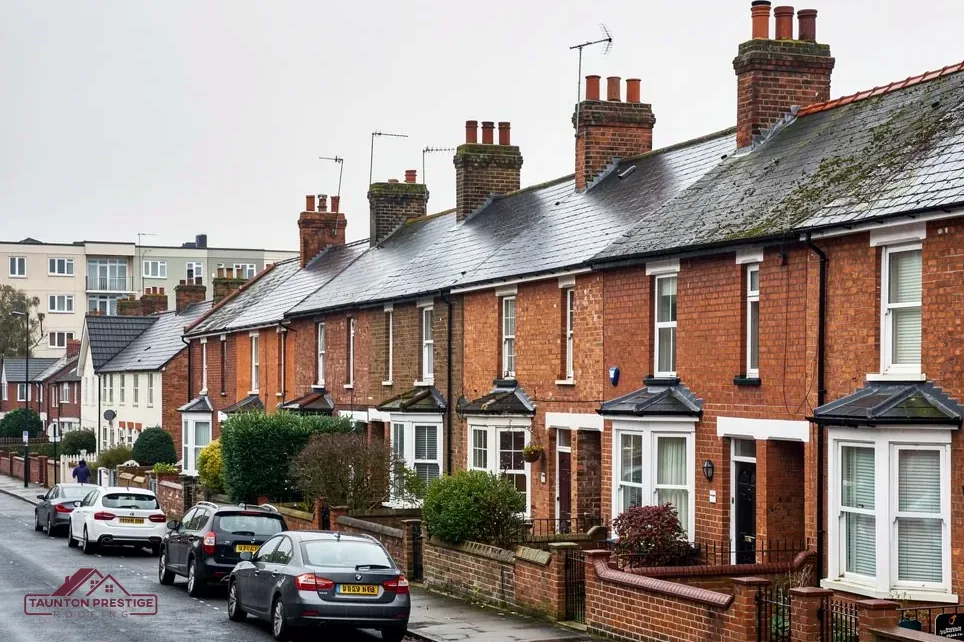 Victorian red-brick terrace with slate roofs and chimneys along a parked street